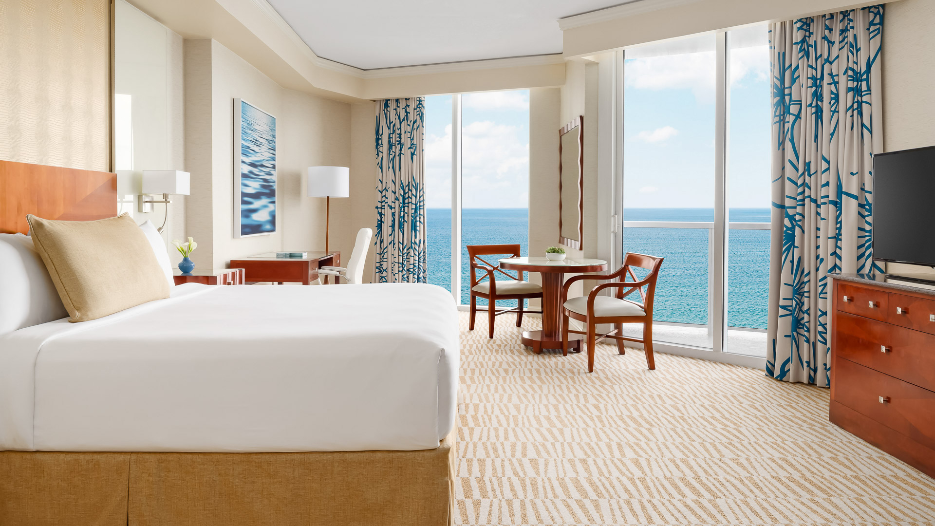 a room with a bed and chairs and a table and chairs overlooking the ocean
