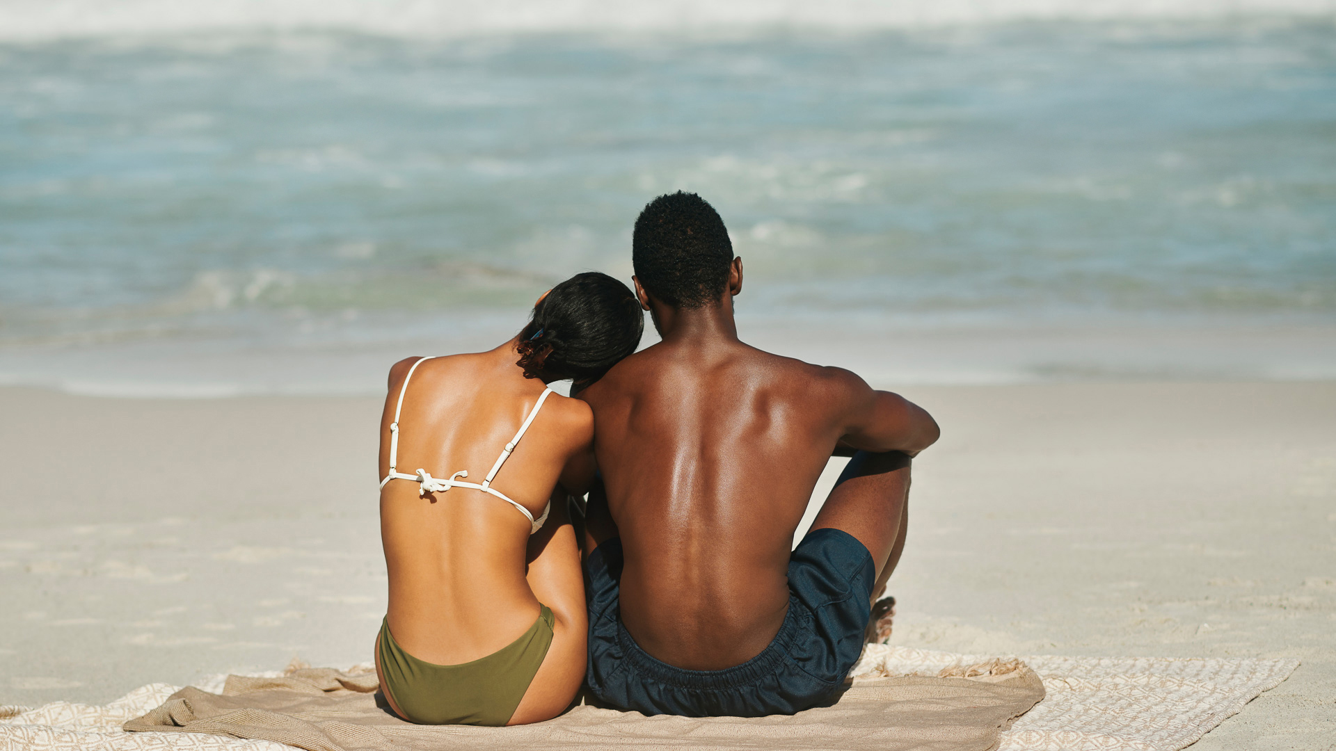 a man and woman sitting on a beach