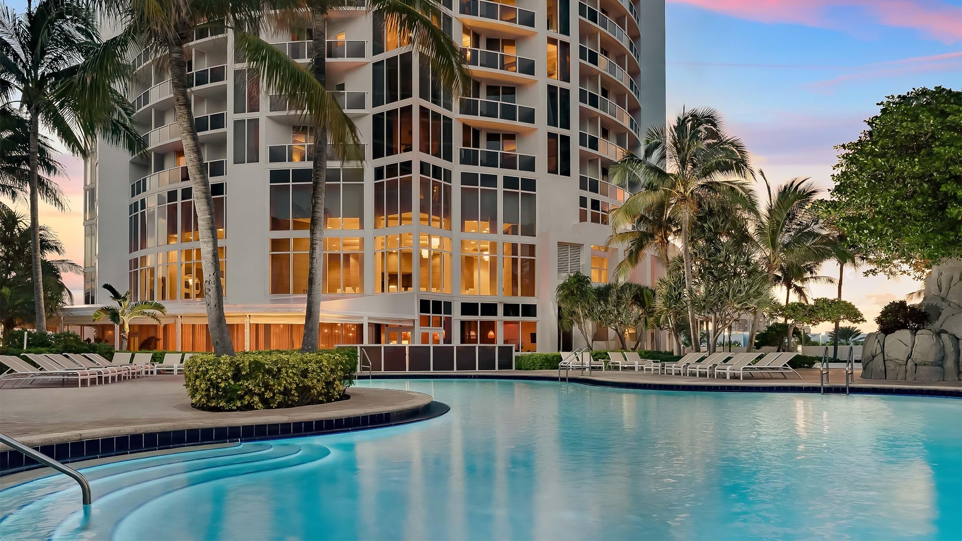 a pool with palm trees and a building
