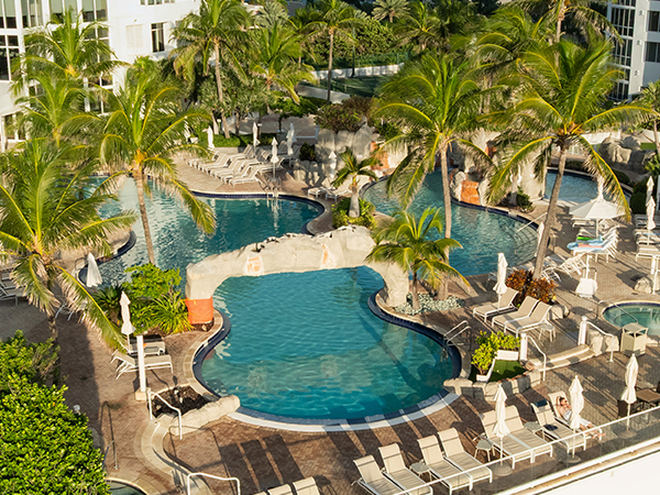 a pool with palm trees and a building