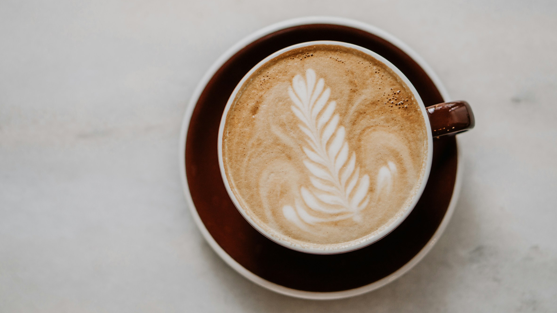 a cup of coffee with a leaf design in the foam