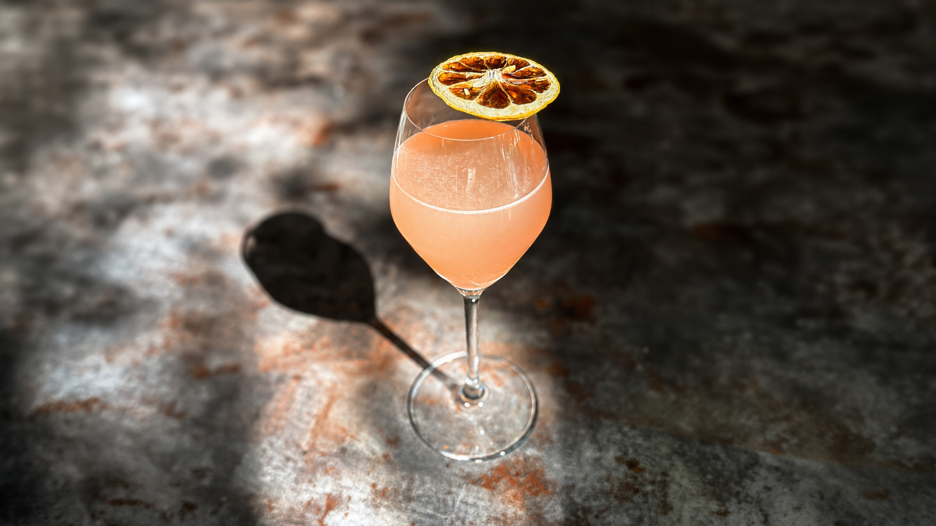 a glass of pink liquid with a slice of orange on top