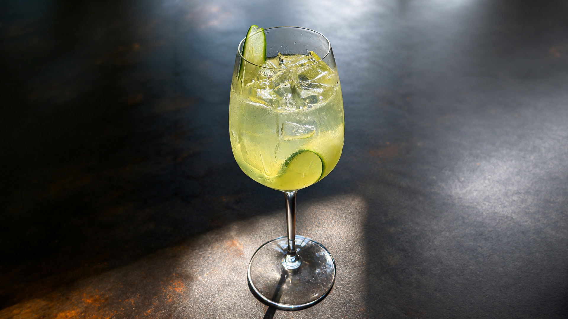 a glass of liquid with a cucumber slice on top
