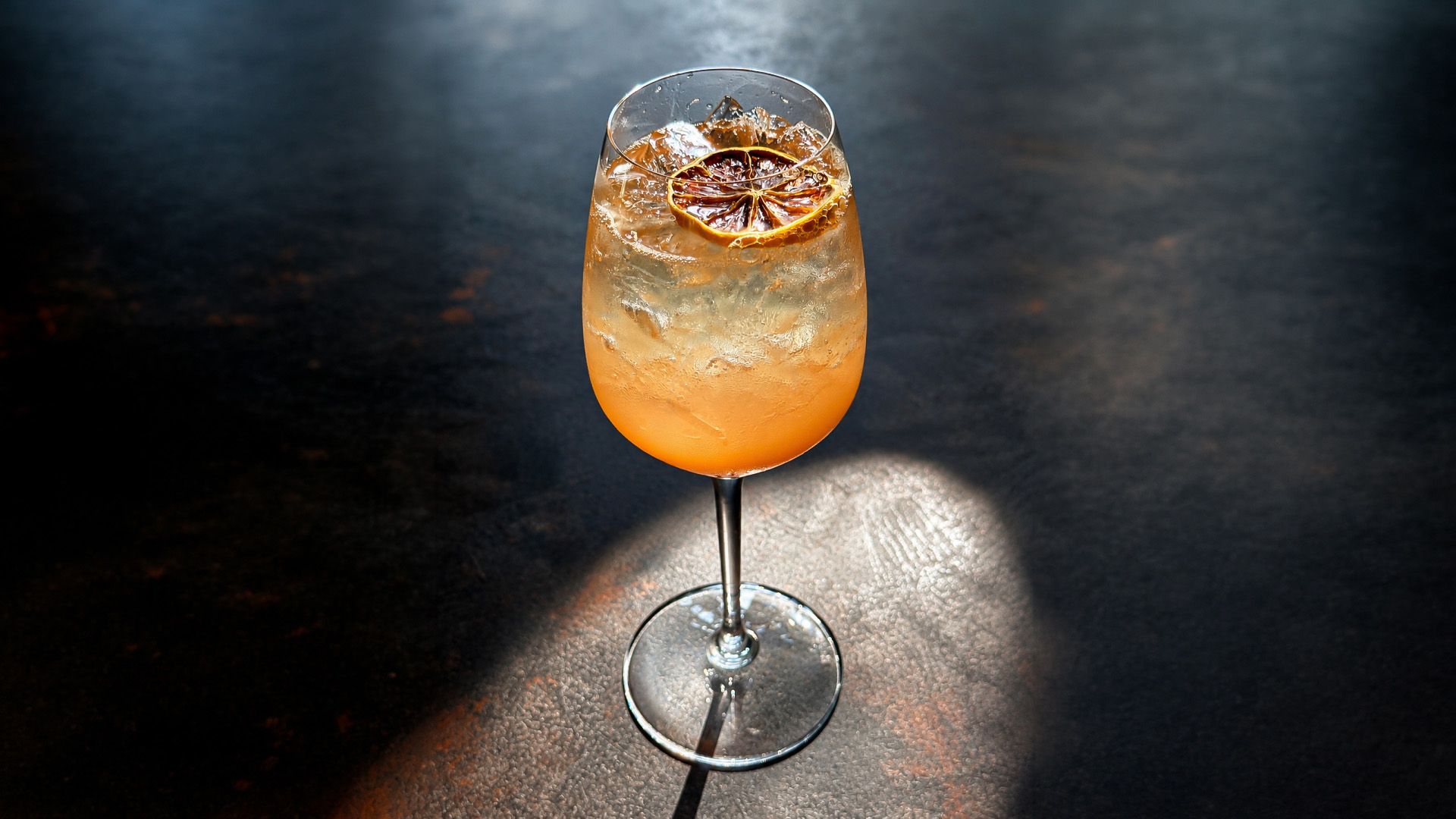 a glass of orange liquid with a slice of orange on top