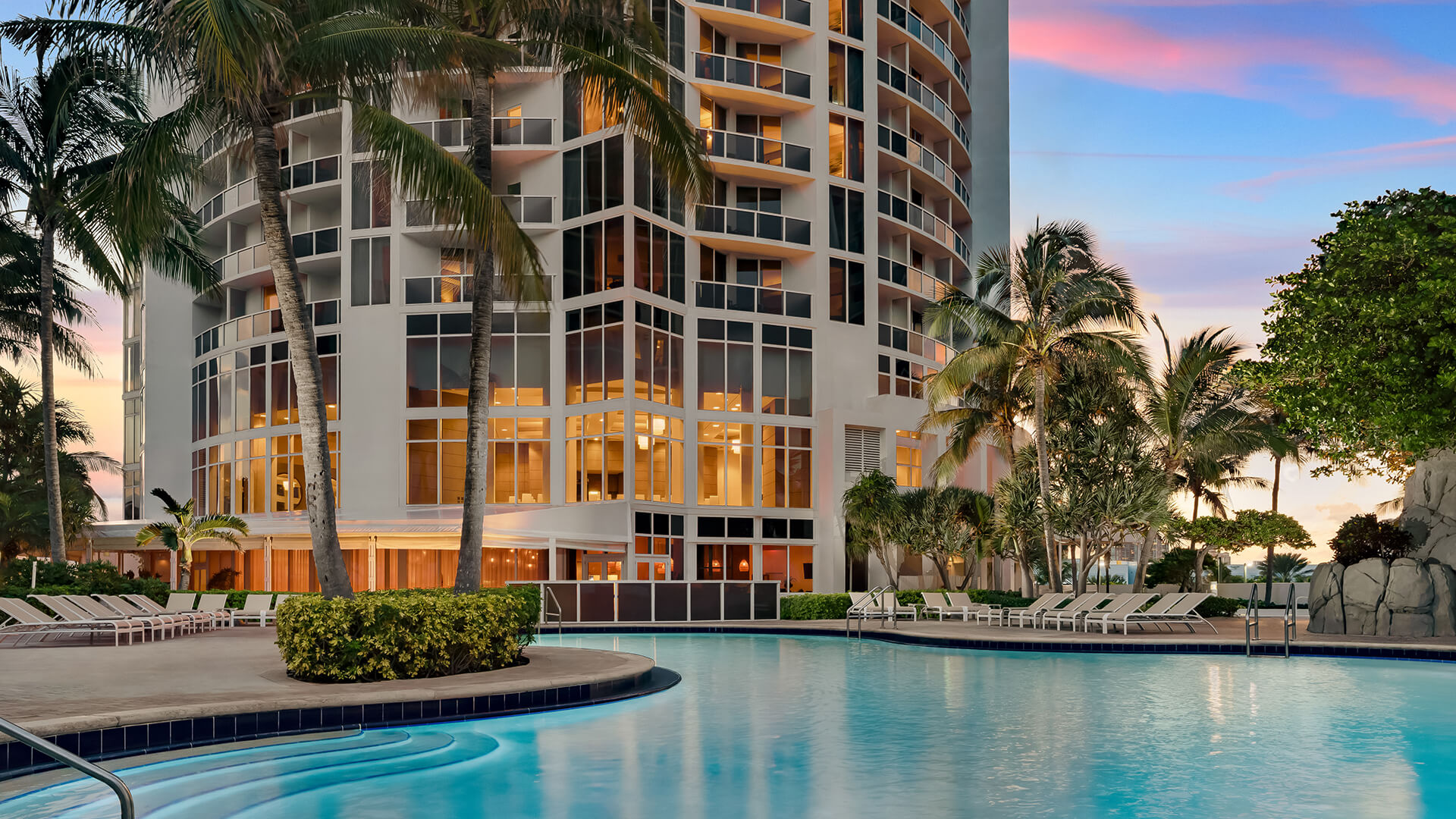 a pool with palm trees and a building
