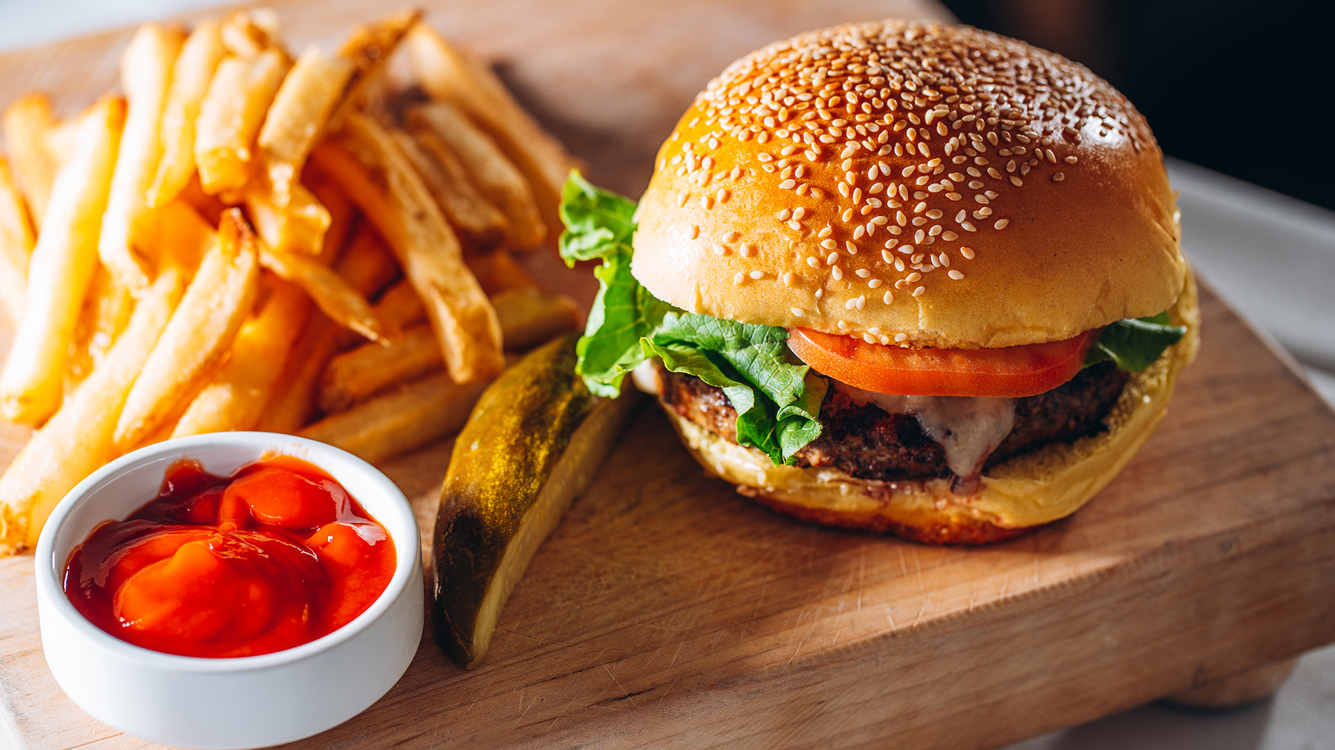 a burger and fries on a wooden board