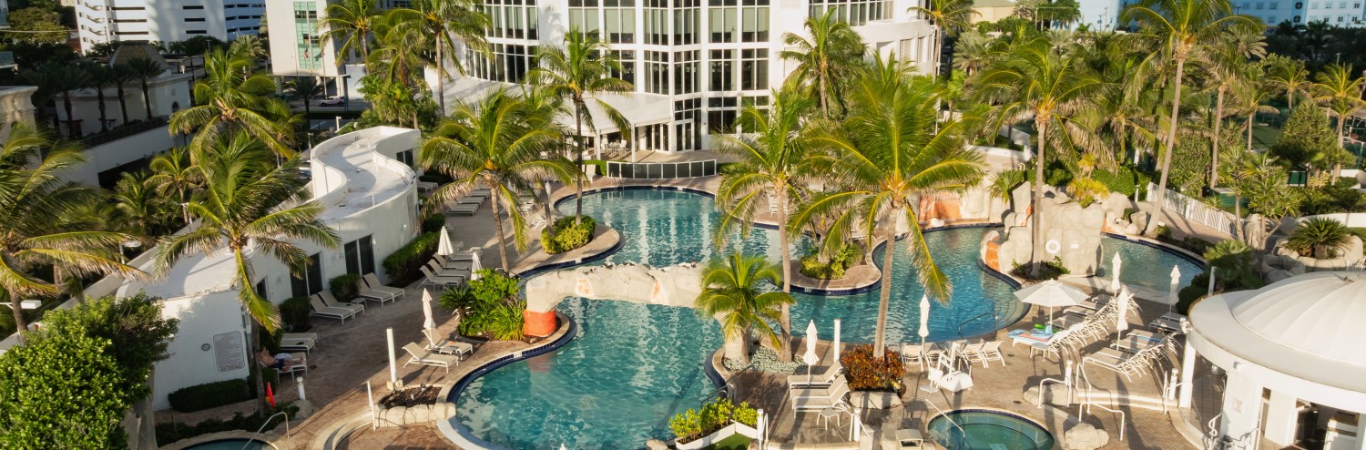 a pool with palm trees and a building in the background