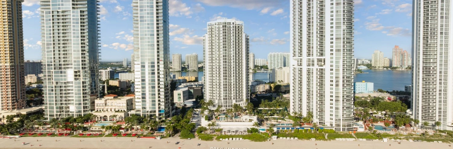 a beach with tall buildings and a body of water