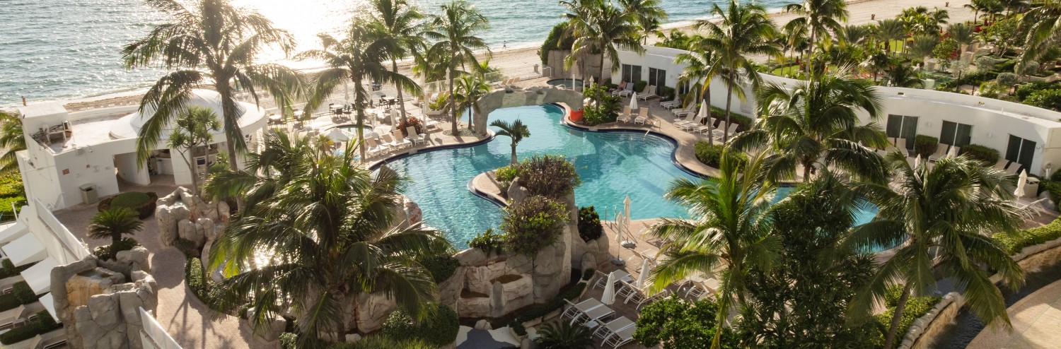 a swimming pool with palm trees and a beach