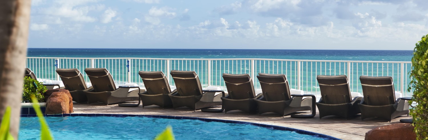 a pool with lounge chairs and a body of water