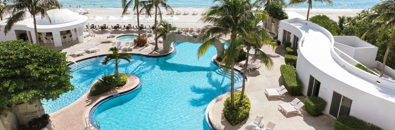 a swimming pool with palm trees and a beach