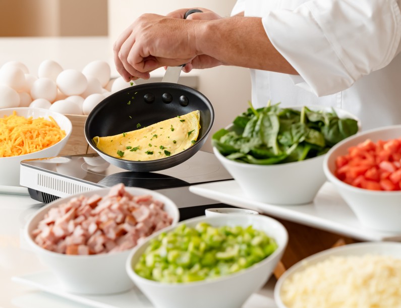 a person cooking omelette in a pan