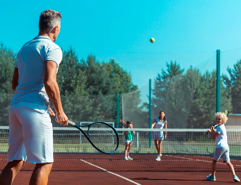 a father playing tennis with his two kids and his wife