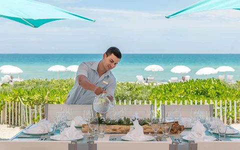 a waiter pouring water into glasses on a table set for dinner