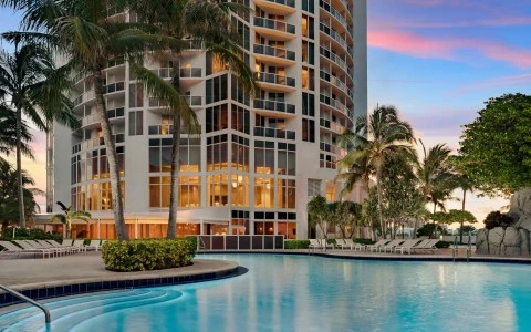 a pool with palm trees and a building with a blue sky
