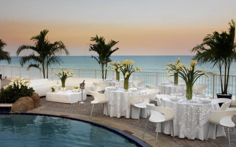 a pool with tables and chairs and palm trees
