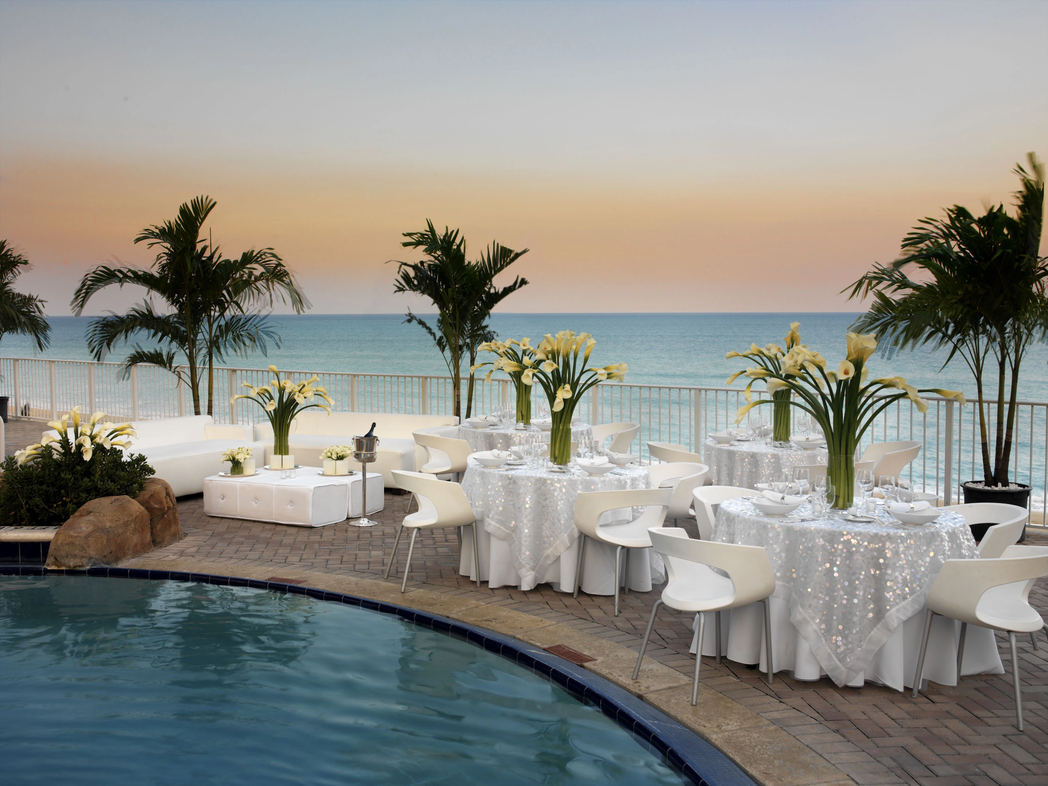 a pool with tables and chairs and palm trees