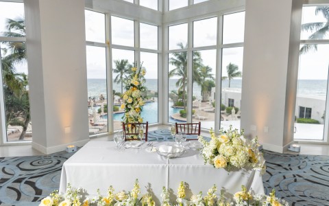 a table with flowers in front of a large window