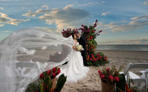 a bride and groom kissing on a beach
