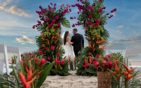 a man and woman standing under a floral arch