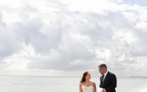a man and woman in wedding attire on a beach