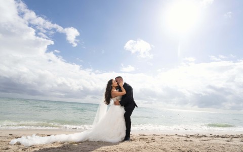a man and woman kissing on a beach