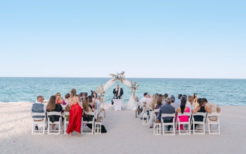 a group of people sitting in chairs at a beach wedding