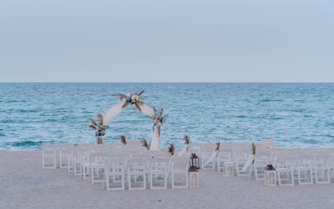 a beach wedding set up with chairs and a arch