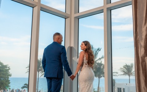 a man and woman holding hands looking out a window