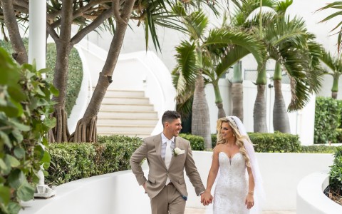 a man and woman in wedding attire walking down a walkway