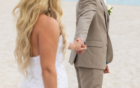 a man and woman holding hands on a beach