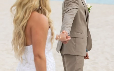 a man and woman holding hands on a beach