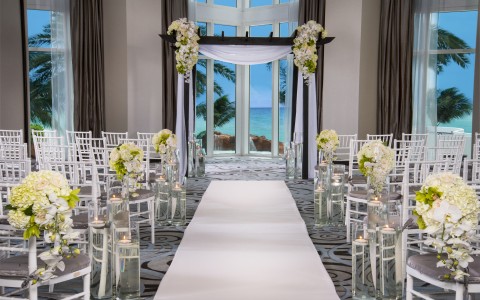 a wedding ceremony with white chairs and flowers