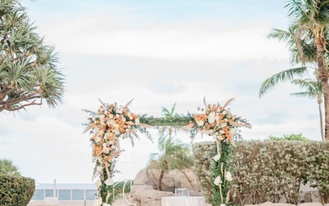 a wedding ceremony set up with a table and chairs and palm trees