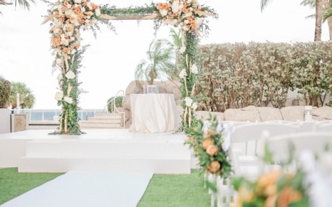 a wedding ceremony with a white and orange arch and chairs