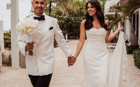 a man and woman holding hands and walking down a brick walkway