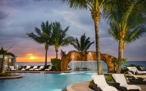 a pool with lounge chairs and palm trees