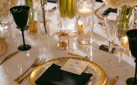 a table with a plate of gold plates and candles