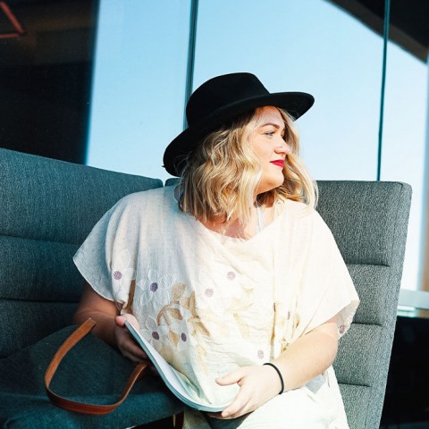 a person in a hat and a white shirt sitting in a chair