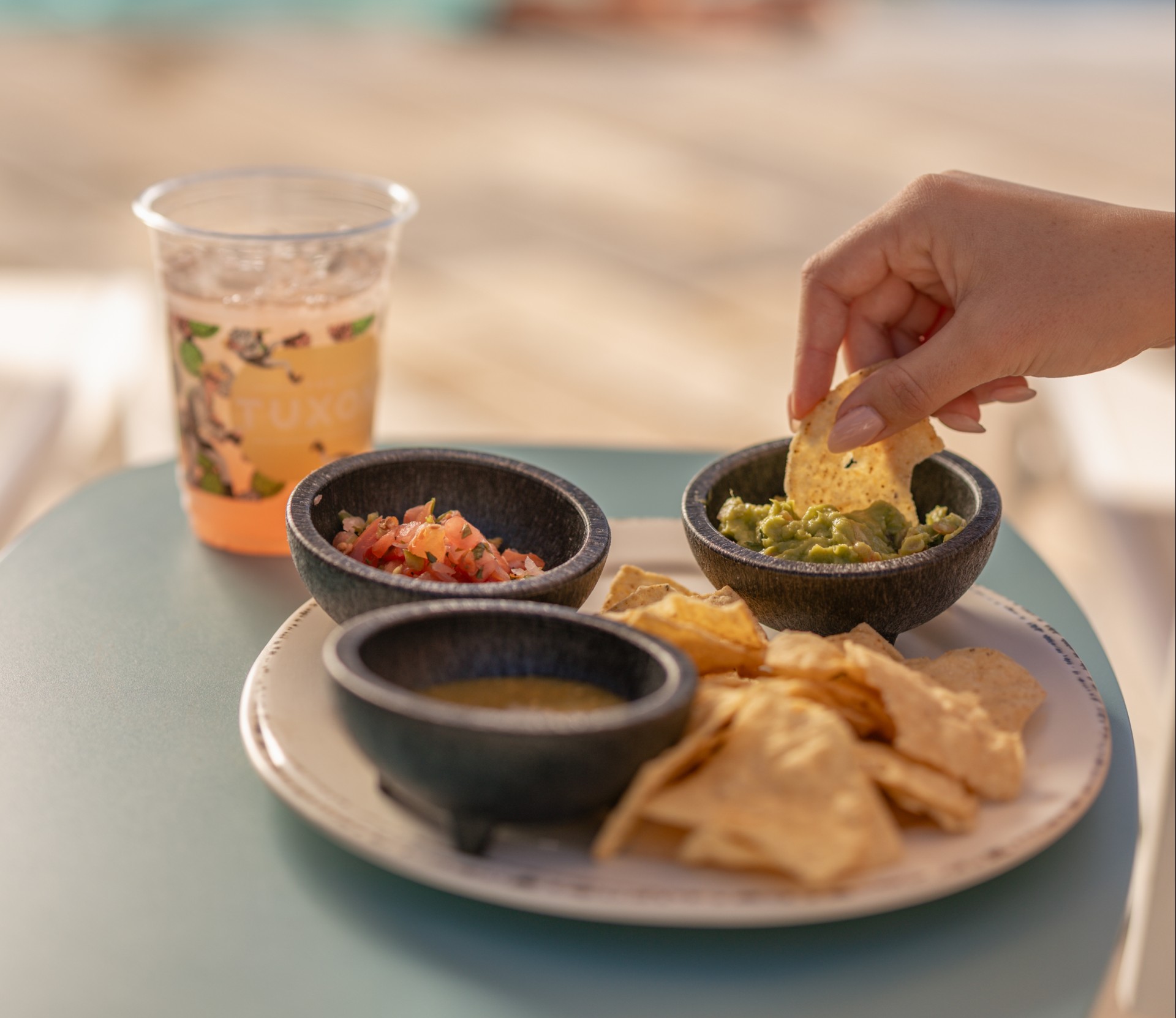 a hand dipping a chip into a bowl of salsa and chips