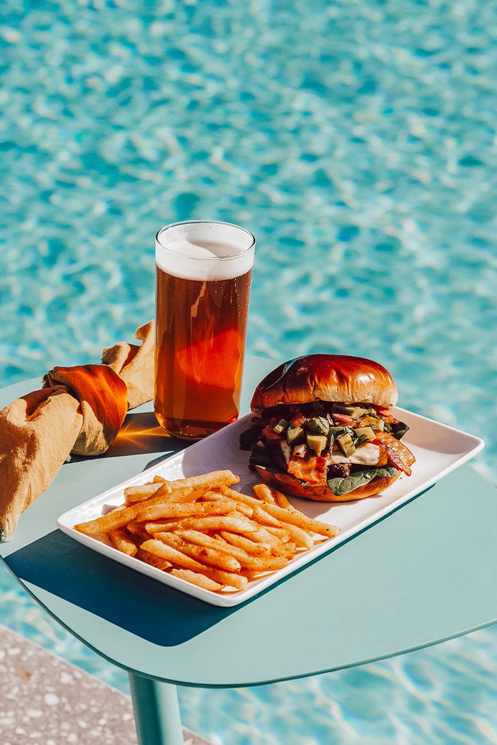 a burger and fries on a plate by a pool