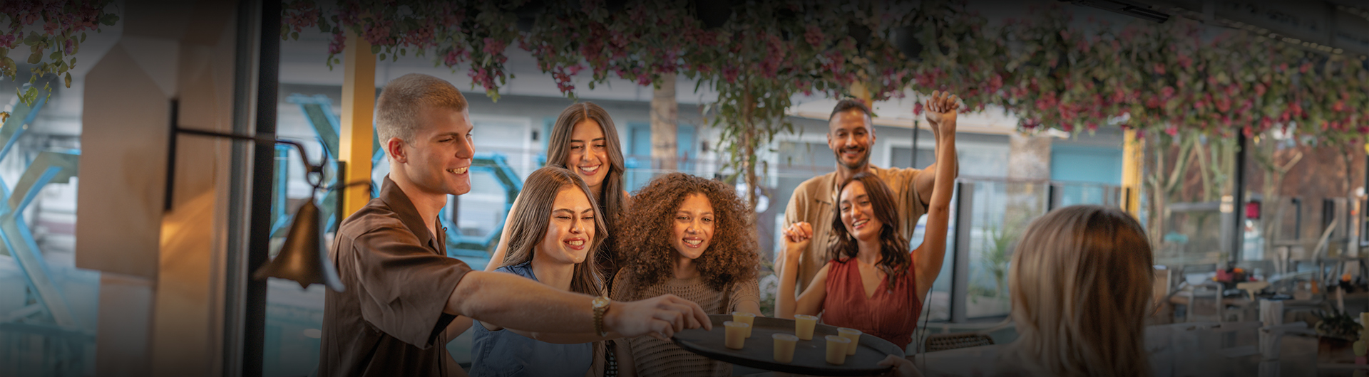 a group of people smiling and holding a tray of shots