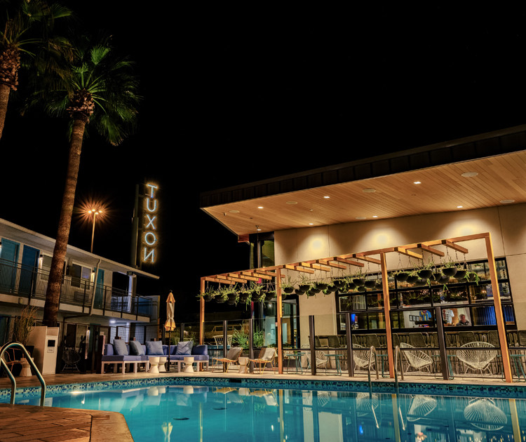 a pool with a lounge chair and umbrellas by a building