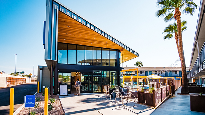 a building with glass walls and a man walking in the sun