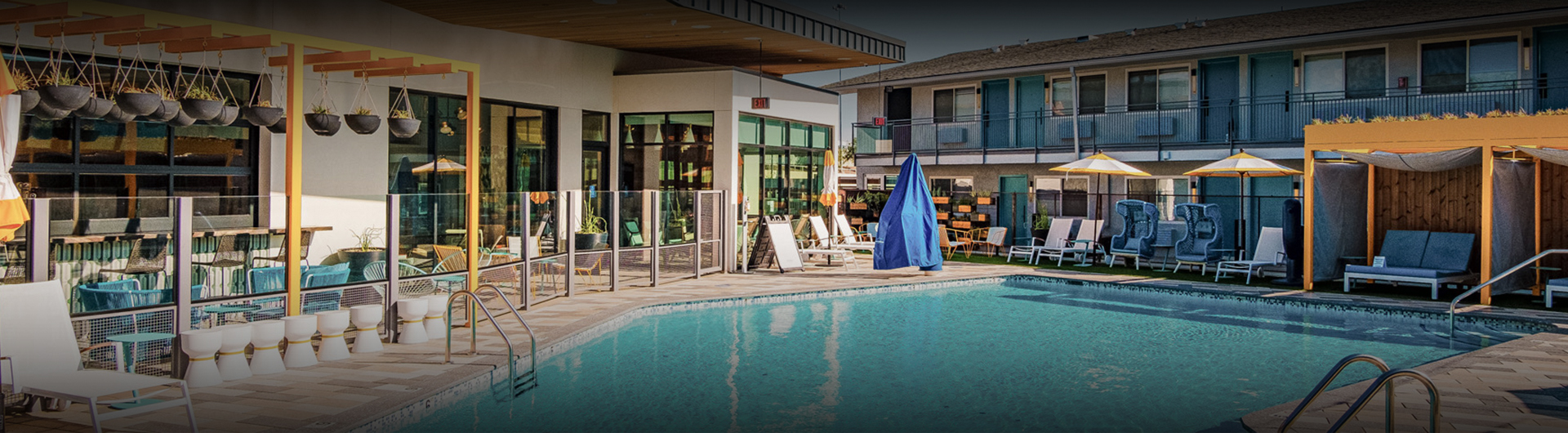 a pool with chairs and umbrellas in front of a building