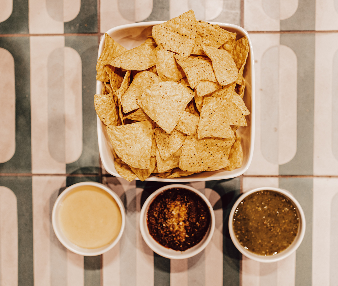a bowl of chips and three bowls of sauce