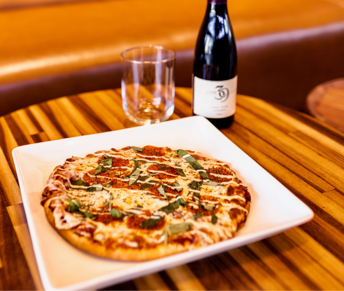 a pizza on a plate with a bottle of wine