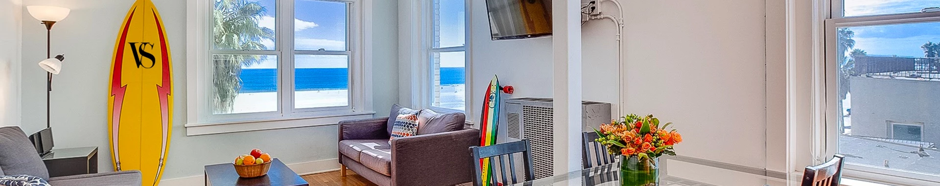 living room area with surfboard, couch and ocean front view 