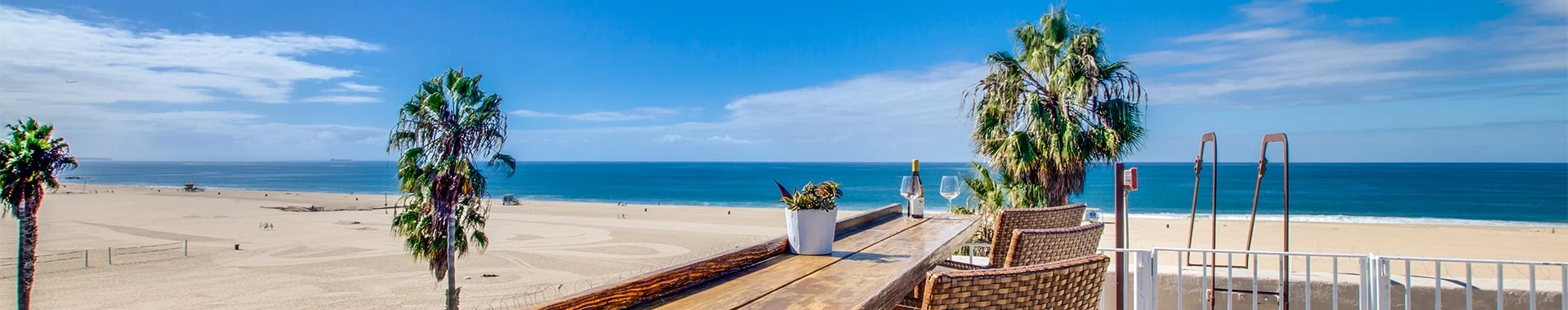 a deck with chairs and a table on it next to a beach
