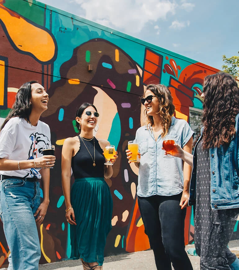 a group of people standing in front of a wall with a mural